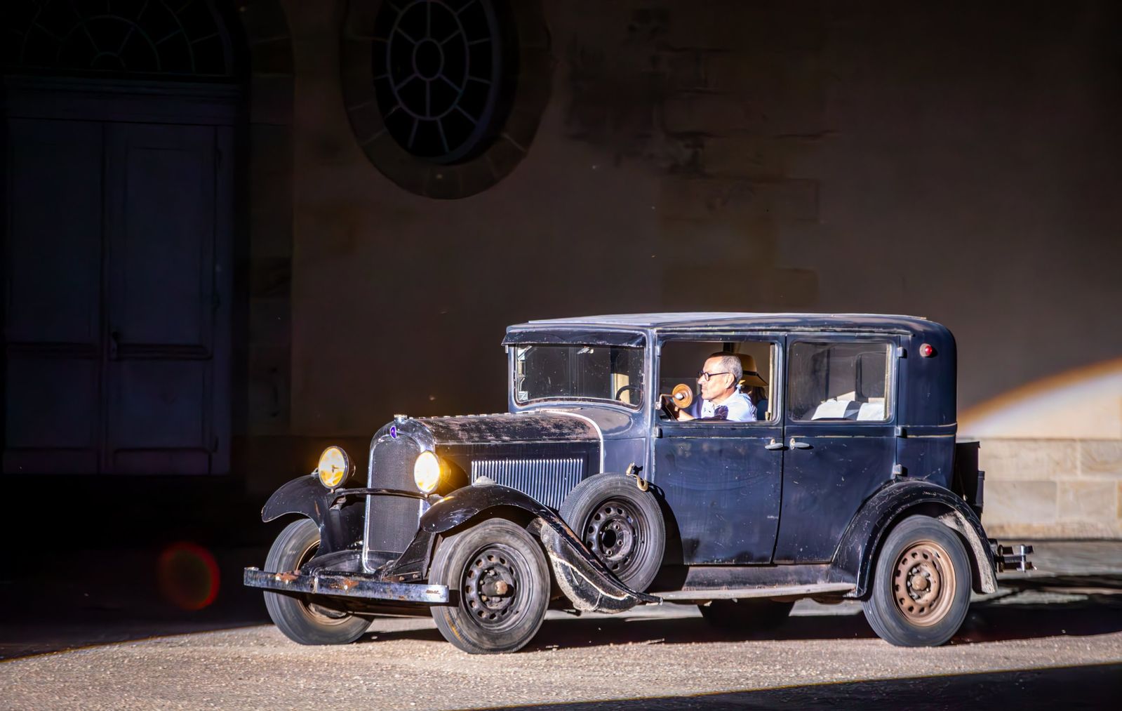 Une automobile ancienne noire sous un projecteur